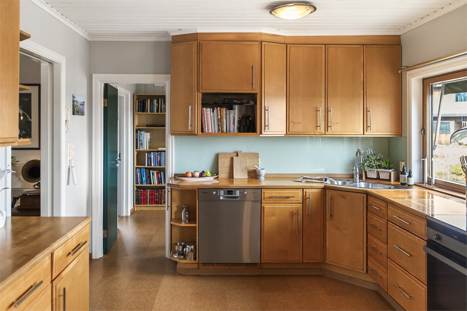 Innredningen har profilerte fronter og benkeplate i tre. Oppvaskmaskin er frittstående.