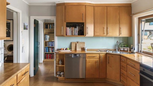 Innredningen har profilerte fronter og benkeplate i tre. Oppvaskmaskin er frittstående.