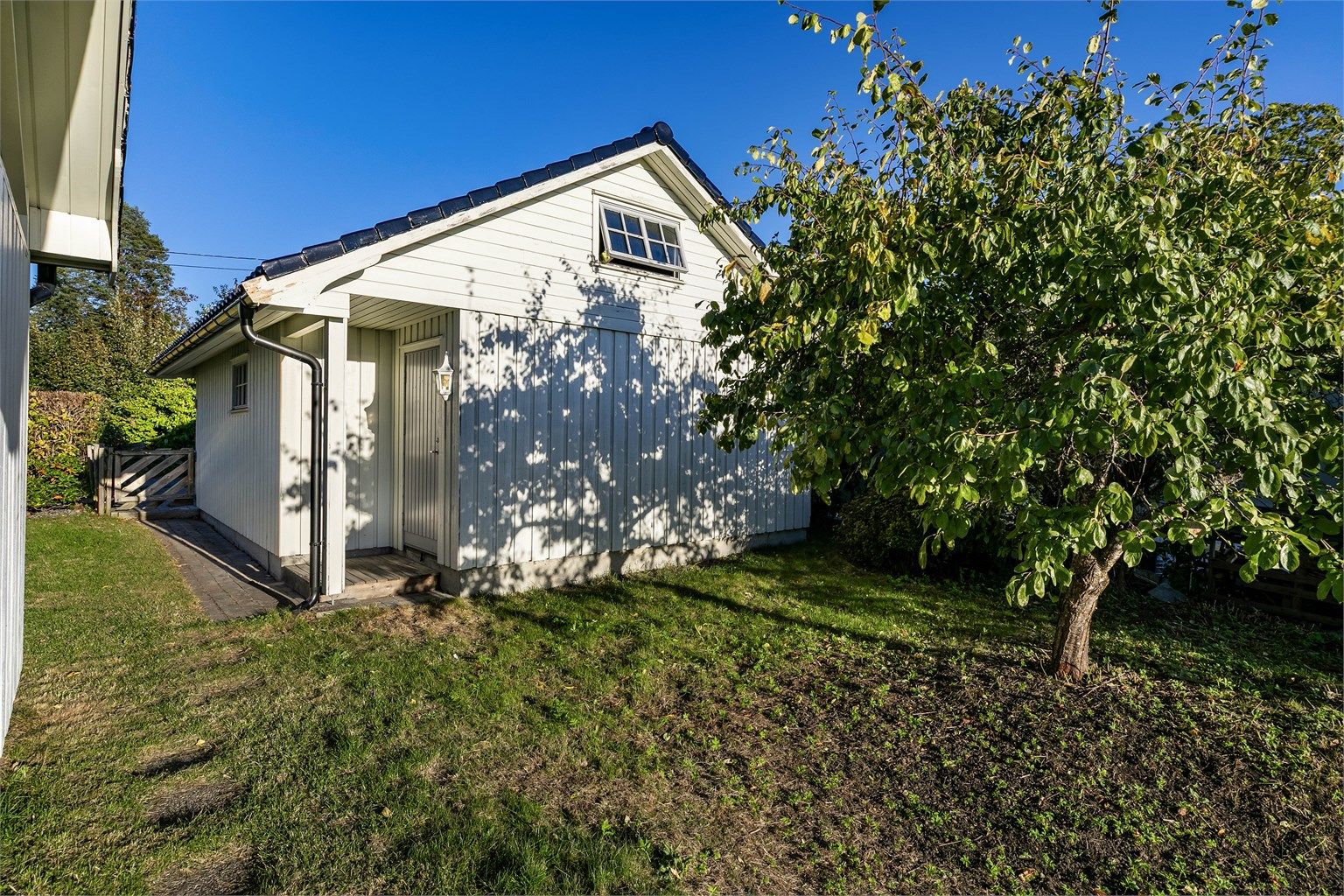 Garasjen har bakdør og loft med lagringsmuligheter.