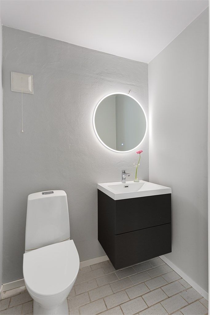 Separat toalettrom med flislagt gulv og vegghengt servantskap.