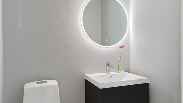 Separat toalettrom med flislagt gulv og vegghengt servantskap.