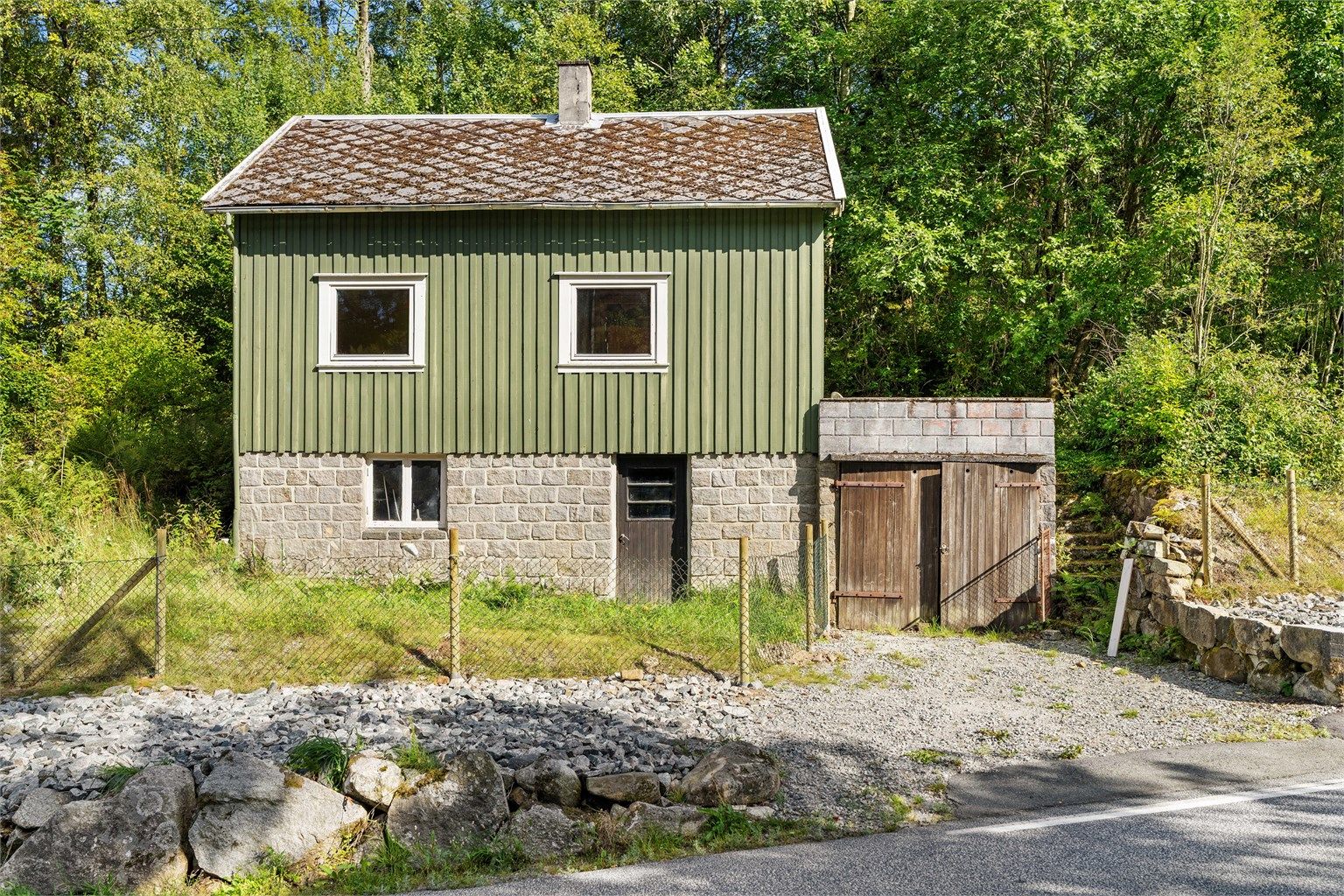 Hytta er oppført med grunnmur av naturstein og stående kledning.