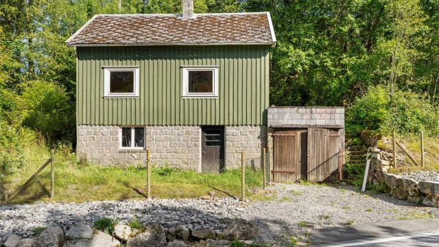 Hytta er oppført med grunnmur av naturstein og stående kledning.
