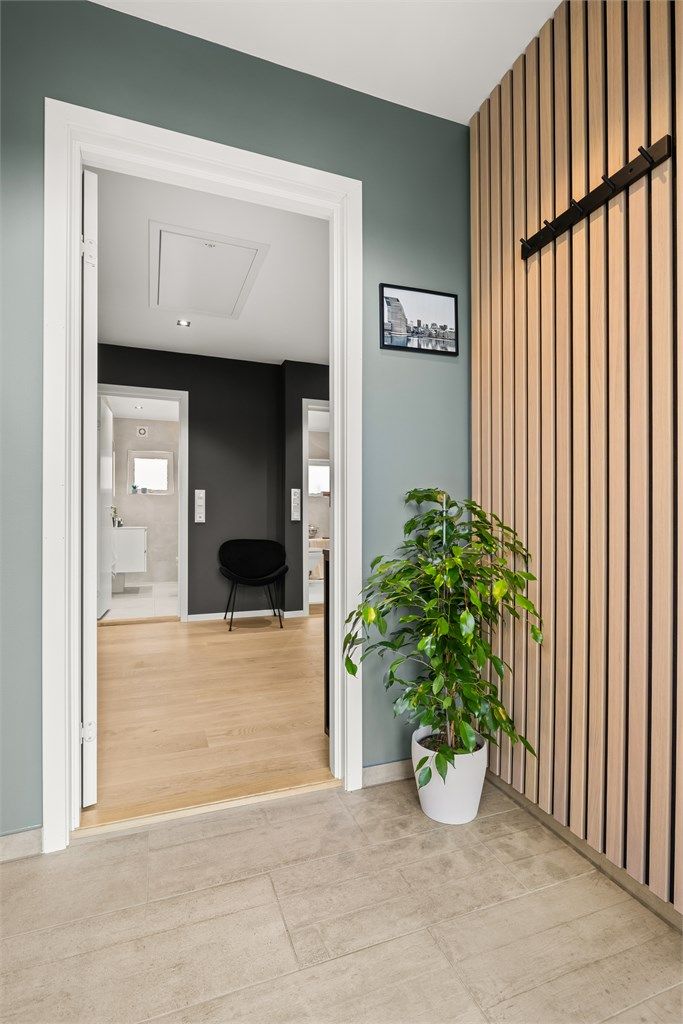Velkommen inn i en lys entré med flislagt gulv og en dekorativ spilevegg.