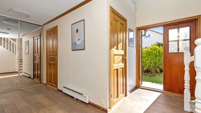 Inngangspartiet leder inn til en lys hall med skyvedørsgarderobe med speilfronter.