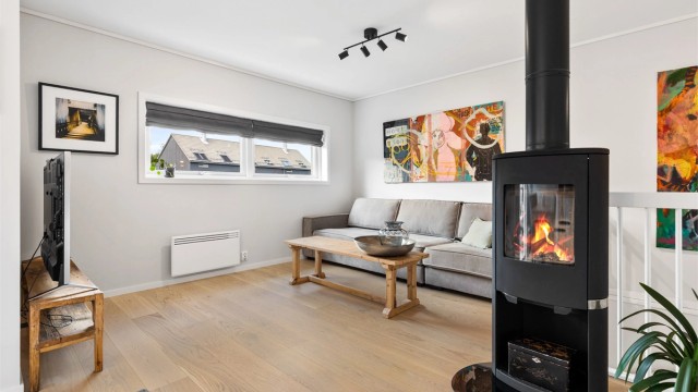 Det er åpen løsning fra kjøkkenet mot stuen og det er god plass til en sofagruppe i stueområdet. Peisen er praktisk plassert, slik at den gir varme til hele etasjen.