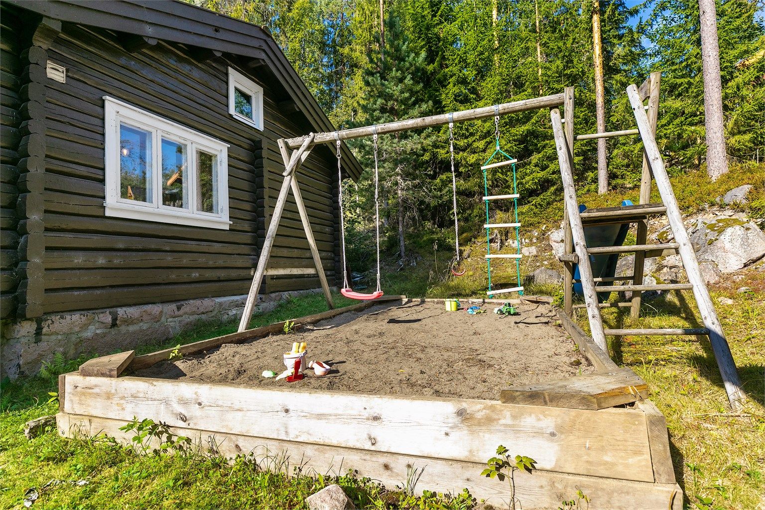 Barnevennlig uteområde med sandkasse, huskestativ og en koselig lekestue som gir små og store mange timer med glede