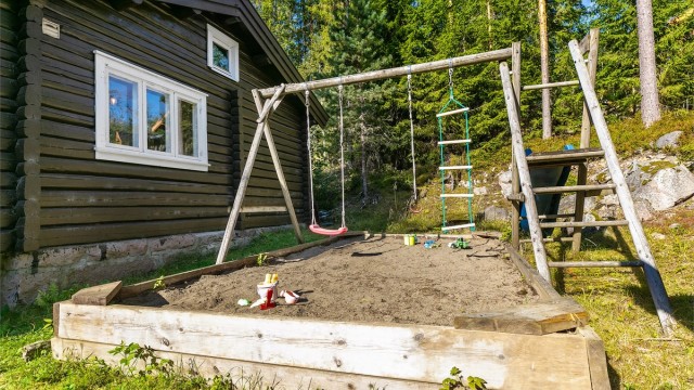 Barnevennlig uteområde med sandkasse, huskestativ og en koselig lekestue som gir små og store mange timer med glede