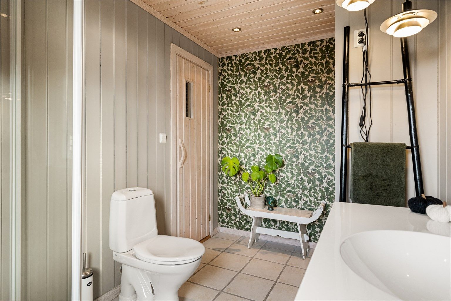 På badet er panelveggene malt i en lysegrå farge. Det gir et delikat uttrykk og en fin helhet mot de hvite gulvflisene.