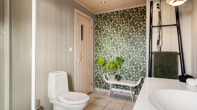 På badet er panelveggene malt i en lysegrå farge. Det gir et delikat uttrykk og en fin helhet mot de hvite gulvflisene.