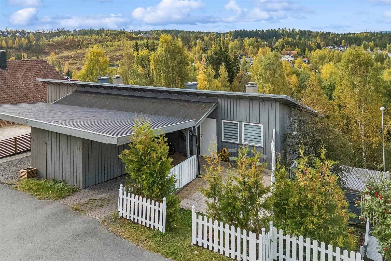 Praktisk carport ved inngangsparti og el-billader montert på husvegg.