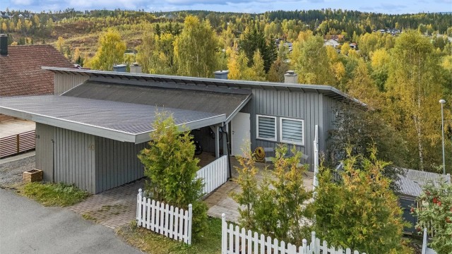 Praktisk carport ved inngangsparti og el-billader montert på husvegg.