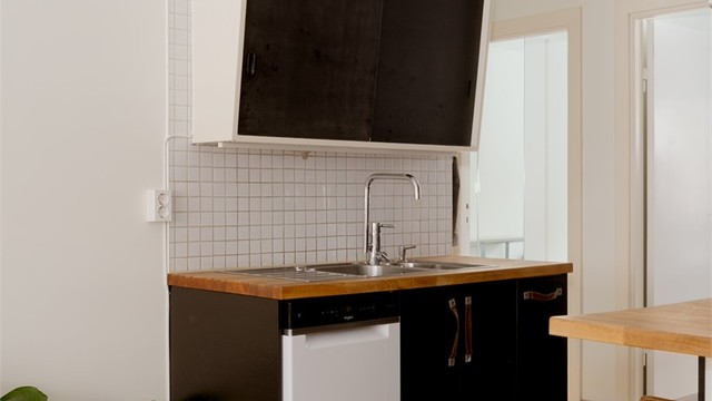 Innredningen består av sorte glatte fronter, benkeplate i heltre, nedfelt oppvaskkum og ett-greps armatur. Innredningen er tilpasset rommets utforming for en god bruk av stue- kjøkkenområdet.