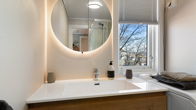 Moderne servantinnredning med et stort, bakbelyst speilskap som gir godt lys og ekstra oppbevaring.