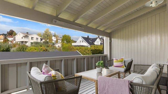 Overbygd terrasse i 2. etasje med dekke av terrassebord, varmeelementer og sittegruppe.