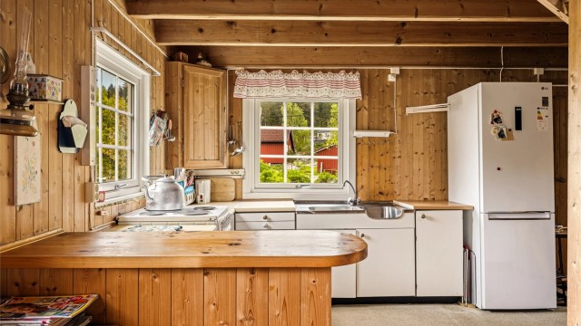 LANDLIG: Enkel kjøkkeninnredning med en benk som skaper skille mot stua.