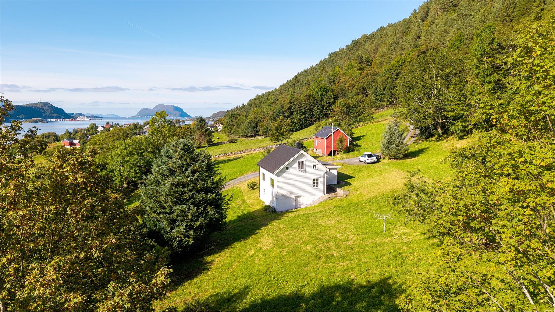Tomten strekker seg oppover i lia mot skogen og åpner seg mot Ellingsøyfjorden.