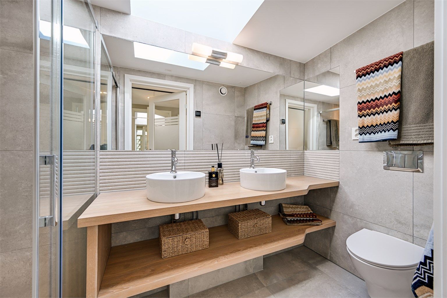 Badet er utstyrt med doble servanter, vegghengt toalett og et romslig dusjhjørne.