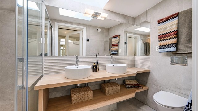 Badet er utstyrt med doble servanter, vegghengt toalett og et romslig dusjhjørne.