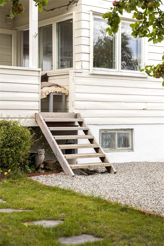 Tretrapp fra verandaen fører direkte ned til den gruslagte uteplassen.