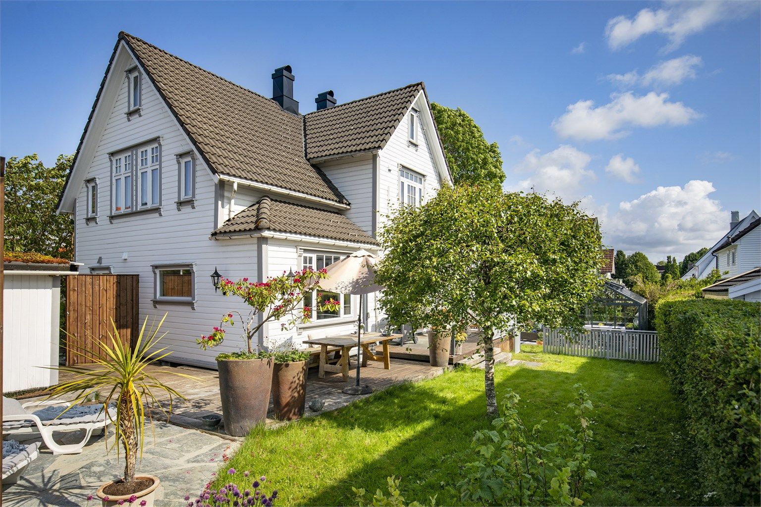 Huset ligger fint til på tomten, omkranset av grøntarealer.