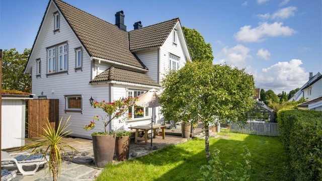 Huset ligger fint til på tomten, omkranset av grøntarealer.