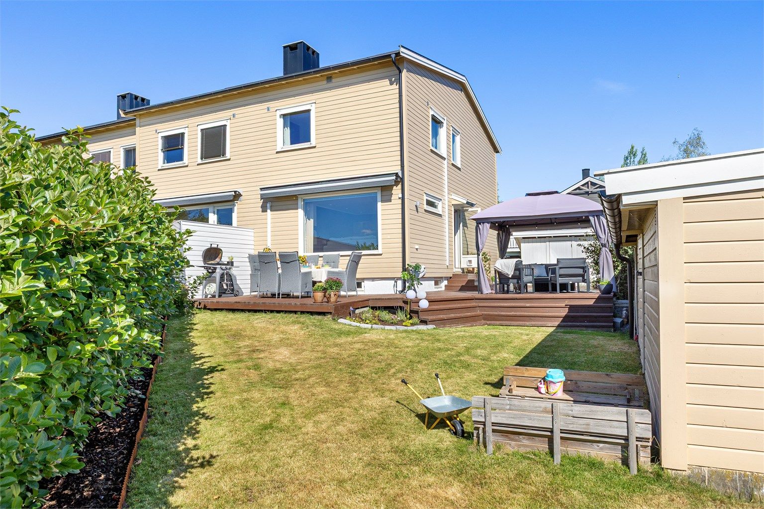 Den romslige hagen med plen, hekk og sandkasse innbyr til timevis med lek i trygge omgivelser.
