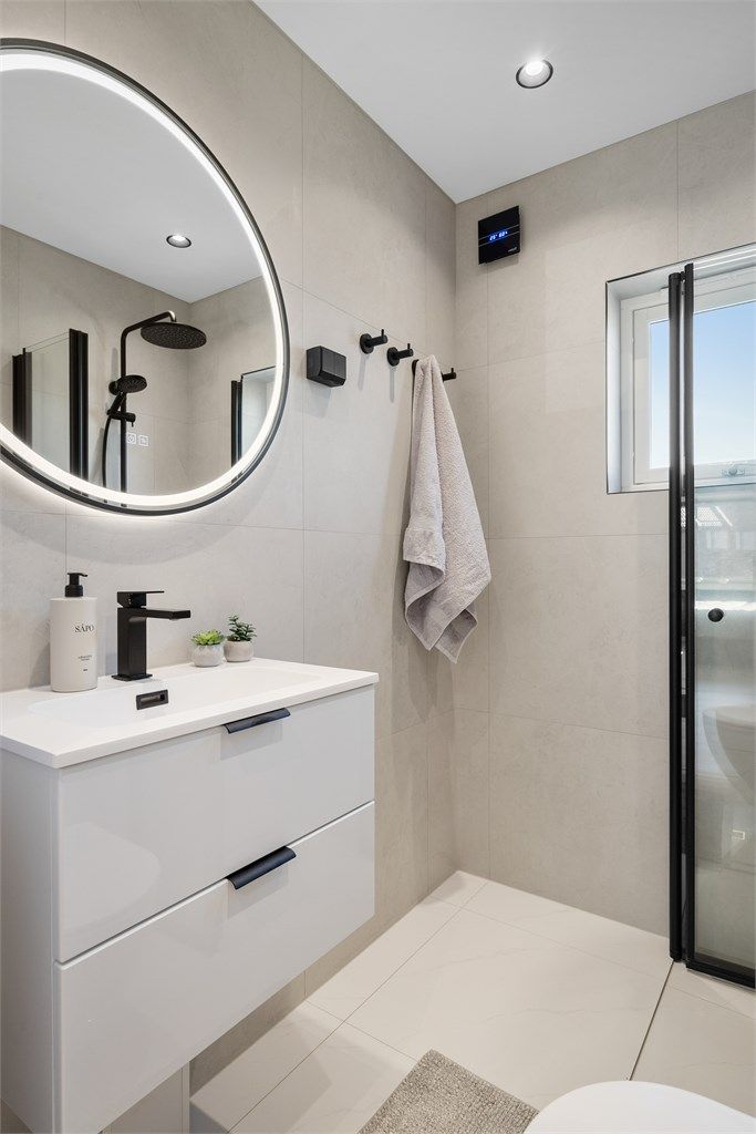 Badet er innredet med vegghengt servant, dusjhjørne og vegghengt toalett