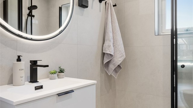 Badet er innredet med vegghengt servant, dusjhjørne og vegghengt toalett