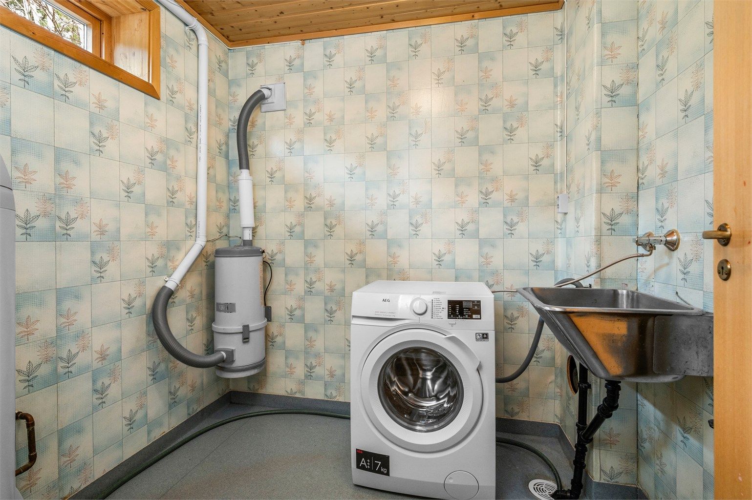 Praktisk vaskerom i underetasjen med opplegg for vaskemaskin, utslagsvask og plass til håndtering av hverdagens behov.