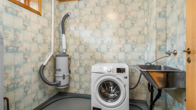 Praktisk vaskerom i underetasjen med opplegg for vaskemaskin, utslagsvask og plass til håndtering av hverdagens behov.