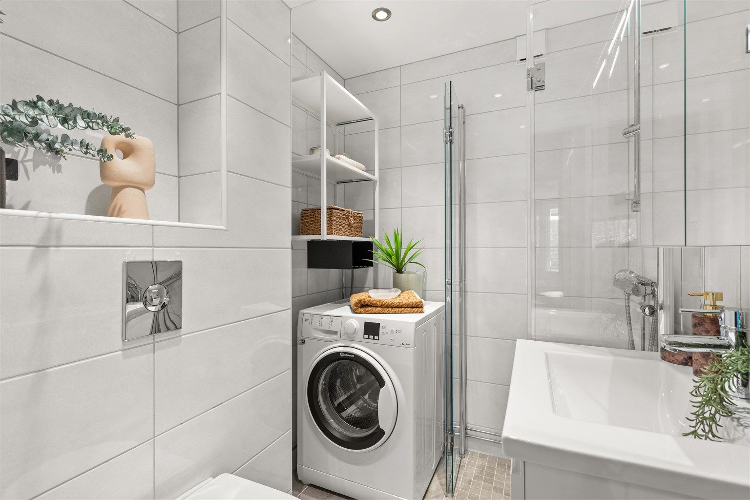 Badet er innredet med vegghengt servantinnredning, heldekkende servant og speilskap med integrert belysning. Dusjhjørne med innfellbare glassdører og vegghengt toalett. Himlingen er nedsenket med downlights som sørger for behagelig belysning.