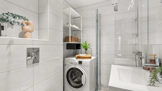 Badet er innredet med vegghengt servantinnredning, heldekkende servant og speilskap med integrert belysning. Dusjhjørne med innfellbare glassdører og vegghengt toalett. Himlingen er nedsenket med downlights som sørger for behagelig belysning.
