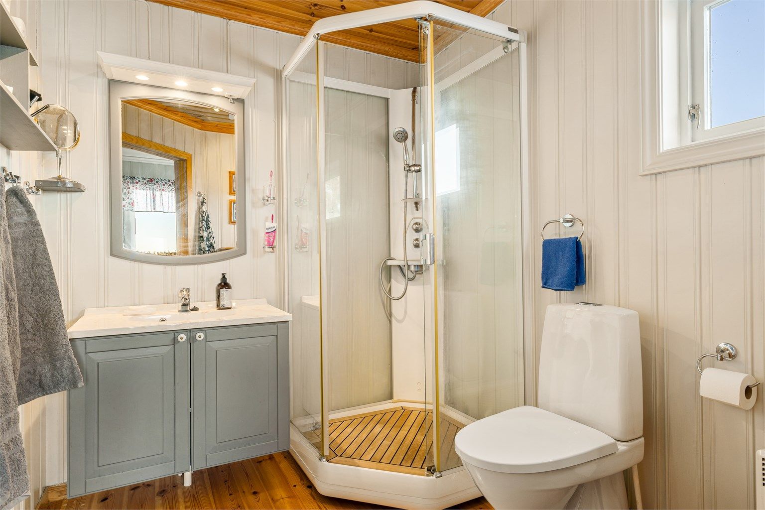 Natet teak i bunn av dusjkabinettet gir luksuriøs og eksklusiv stemning.