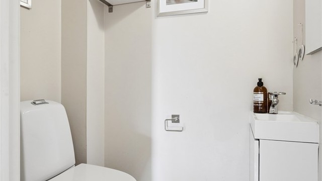 Toalettrom med flislagt gulv og malte overflater på vegger og tak. Innredet med toalett og servant.