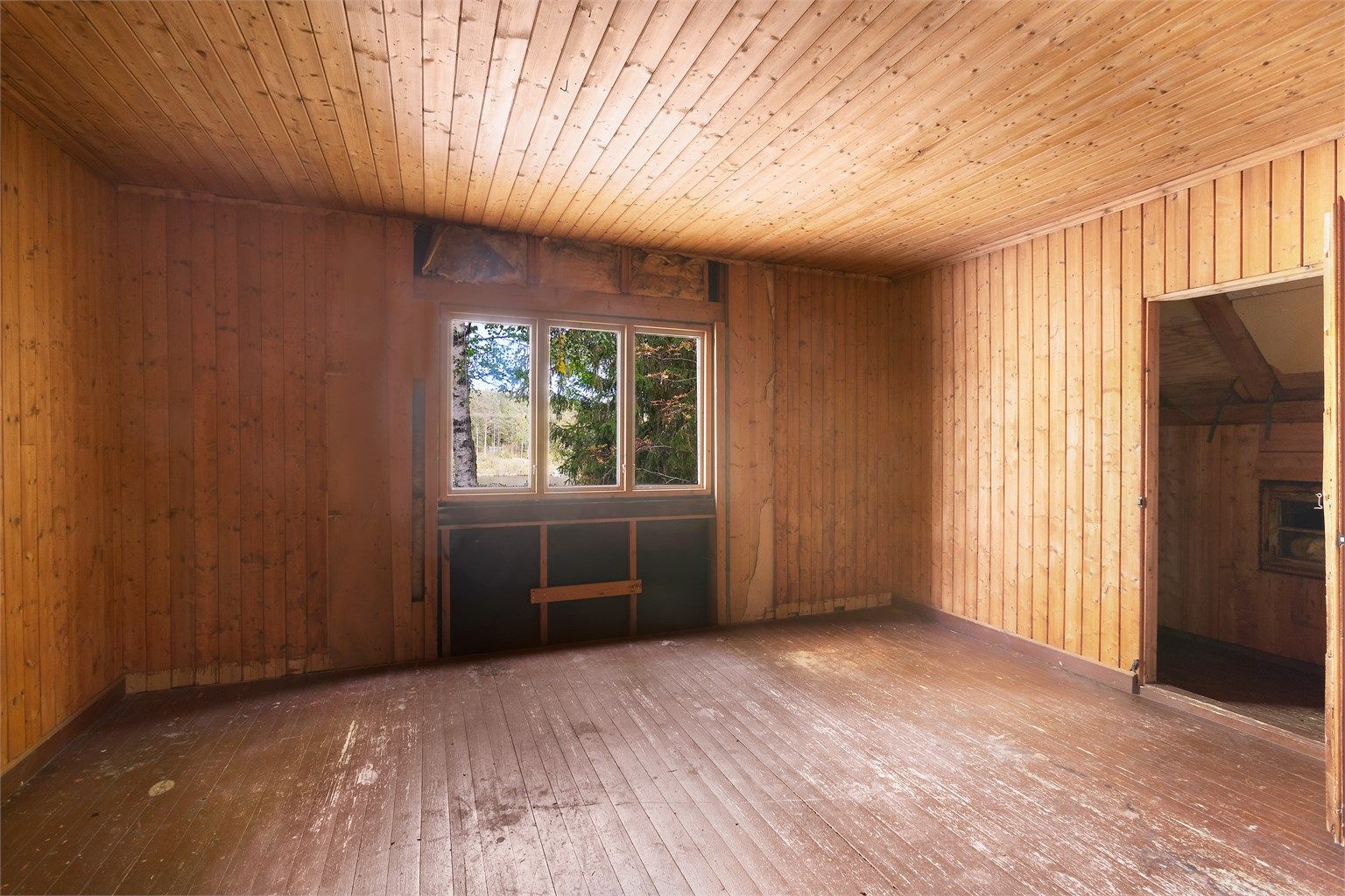 Soverom på loftet med furupanel, tregulv og dør til kott og bod.