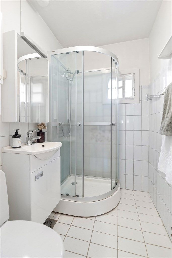 Badet er utstyrt med dusjkabinett, servantinnredning og varme i det flislagte gulvet.