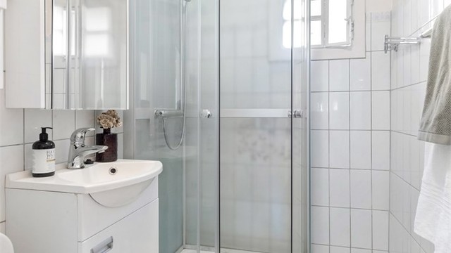 Badet er utstyrt med dusjkabinett, servantinnredning og varme i det flislagte gulvet.