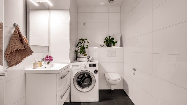 Badet er innredet med vegghengt toalett, servantinnredning med heldekkende vask og speil med lys over vasken. Det er opplegg for vaskemaskin.