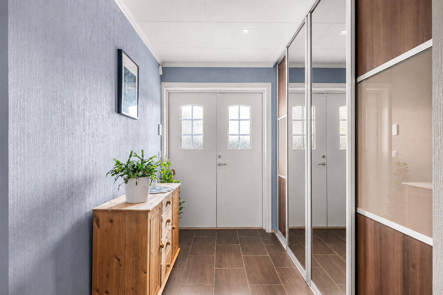 Velkommen inn i en flislagt entré med vannbåren gulvvarme og praktisk skyvedørsgarderobe for oppbevaring av yttertøy og sko.