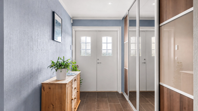 Velkommen inn i en flislagt entré med vannbåren gulvvarme og praktisk skyvedørsgarderobe for oppbevaring av yttertøy og sko.