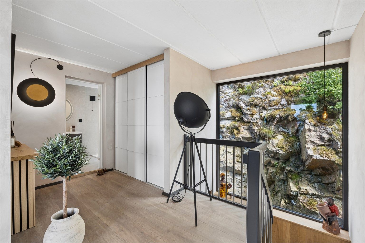 Romslig hall med stor skyvedørsgarderobe og trapp ned til 1. etasje. Legg merke til vinduet som er som et maleri i seg selv!