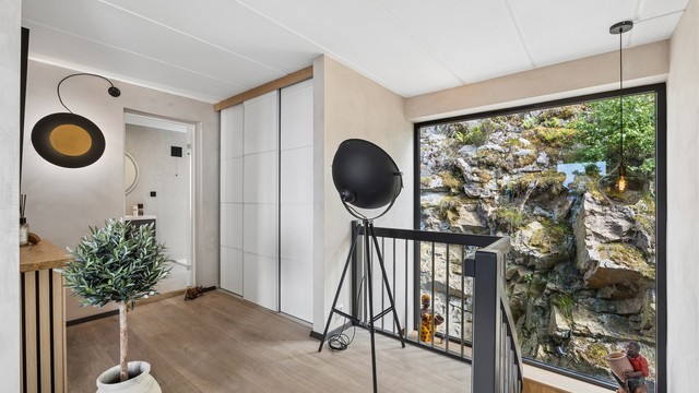 Romslig hall med stor skyvedørsgarderobe og trapp ned til 1. etasje. Legg merke til vinduet som er som et maleri i seg selv!
