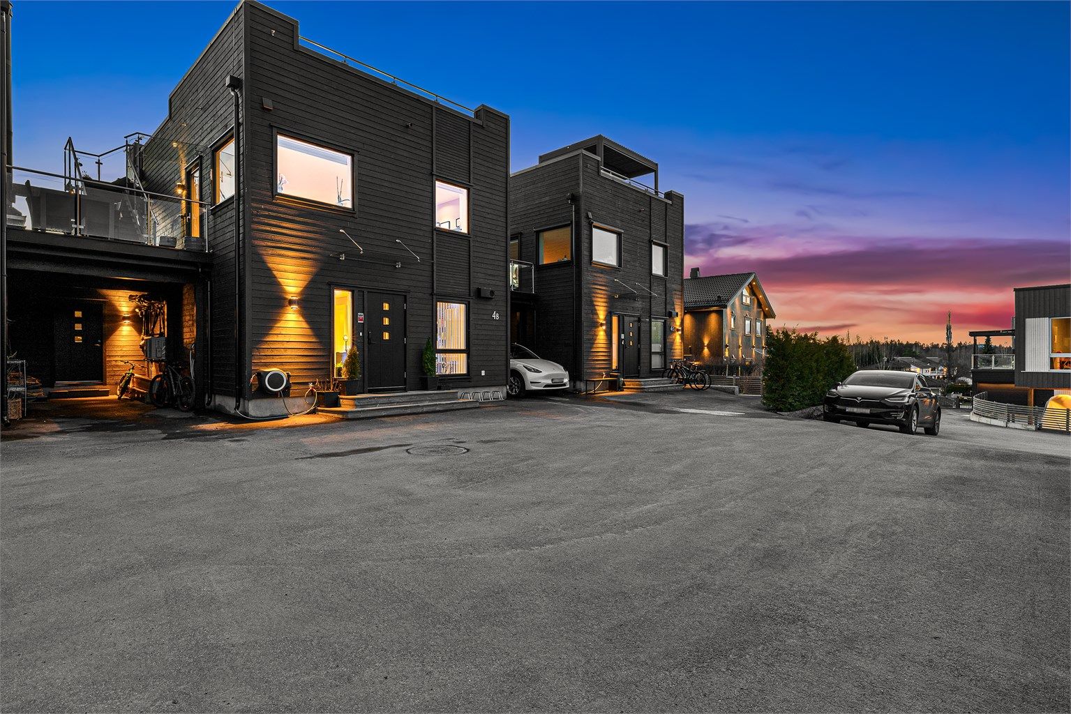 Asfaltert gårdsplass med biloppstillingsplasser og carport.