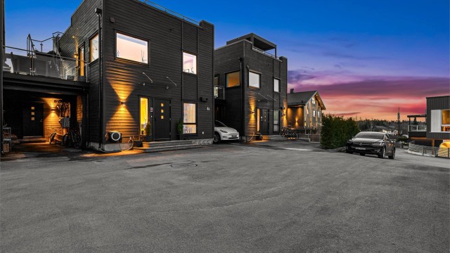 Asfaltert gårdsplass med biloppstillingsplasser og carport.