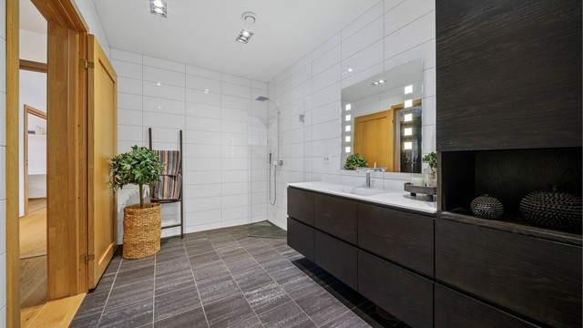 Hovedsoverommet har én-suiteløsning med direkte tilkomst til eget, privat baderom. Baderommet har flislagte gulv med gulvvarme og flislagte vegger. Dusjsonen er pent avgrenset med glassdør