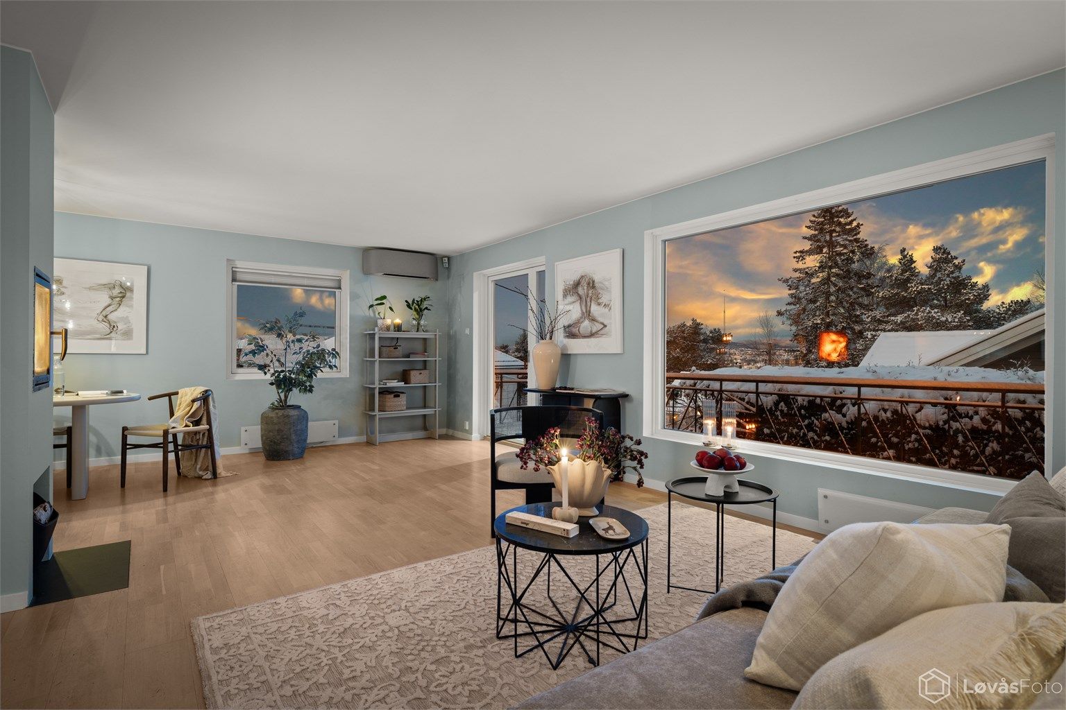 Lys og romslig stue/spisestue med peis og store vindusflater med noe utsikt