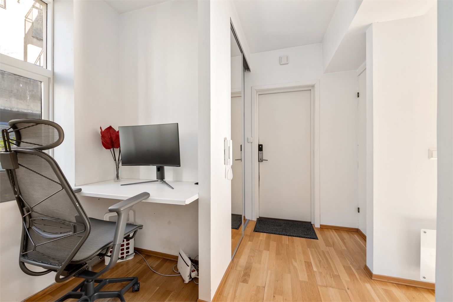 Entréen har god og plassbesparende garderobeløsning i skyvedørsgarderobe med speilfronter. Praktisk innhuk med plass til kontorløsning