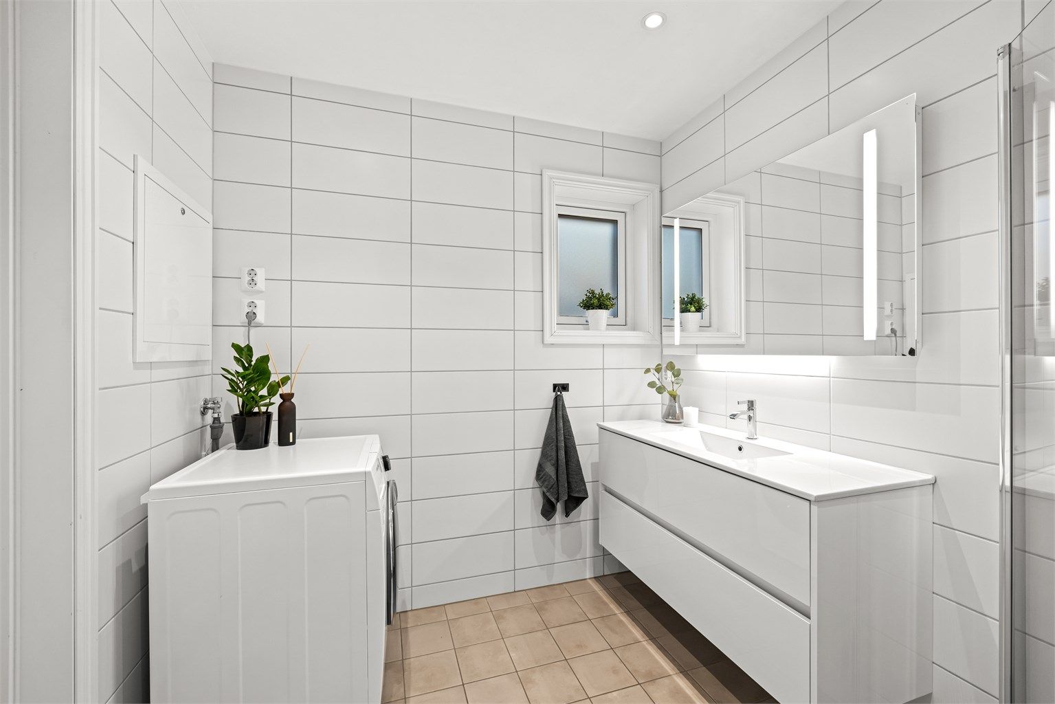 Baderomsinnredningen har heldekkende servant og speil med integrert belysning.