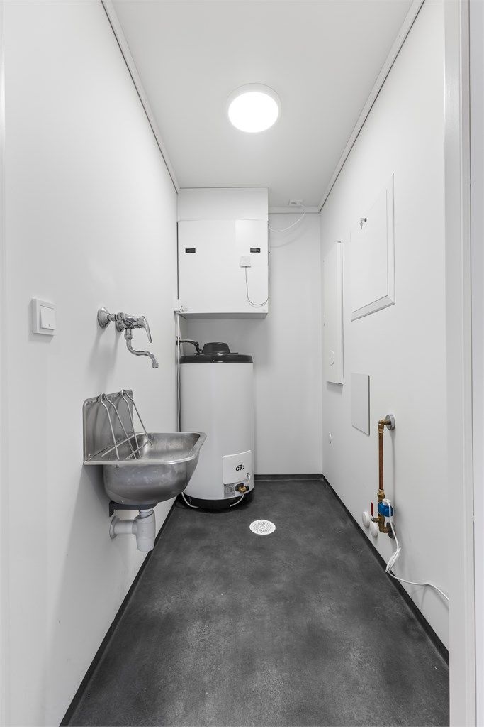Praktisk teknisk rom med opplegg for vaskemaskin og plass til oppbevaring.